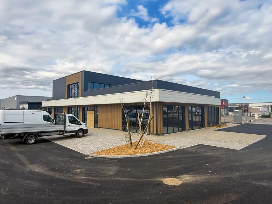Bâtiment commercial moderne avec facade mixte bois et métal, grandes baies vitrées, architecture contemporaine à toit plat