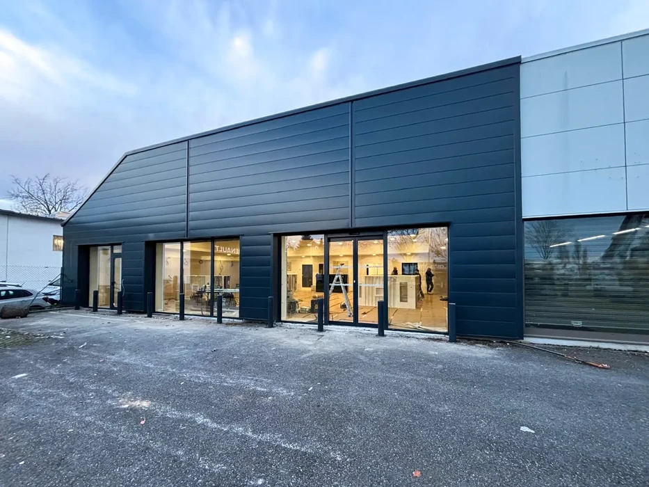 Extérieur d'un bâtiment commercial moderne avec façade en bardage métallique horizontal gris anthracite