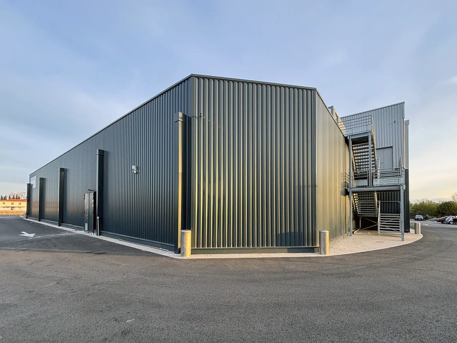 Bâtiment industriel moderne avec façade en bardage métallique nervuré gris-bleu