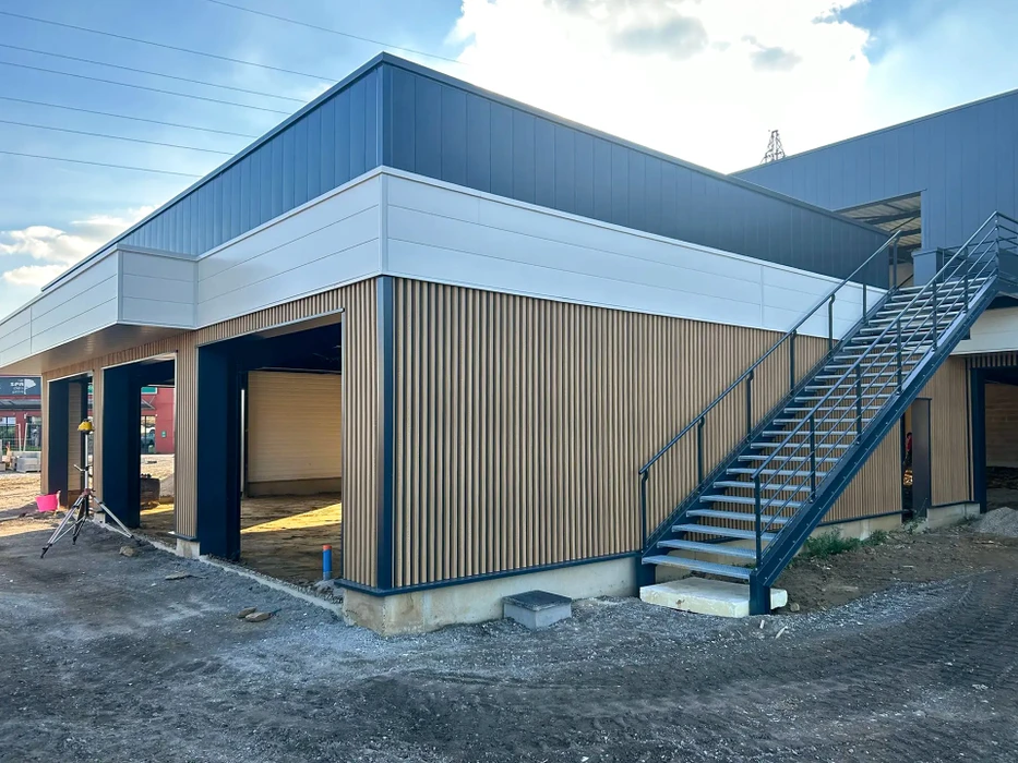 Bâtiment industriel moderne en construction avec façade en bardage métallique gris