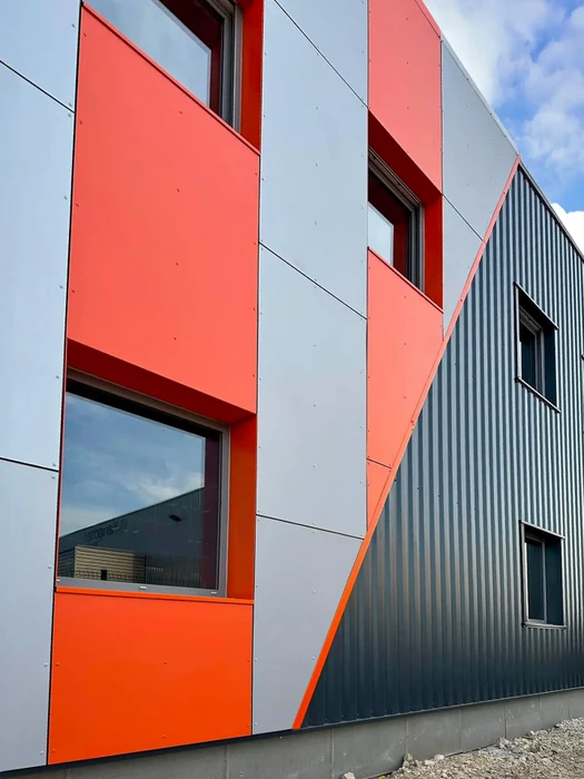 Façade extérieure d'un bâtiment industriel moderne avec bardage métallique à nervures verticales alternant bandes bleues et grises